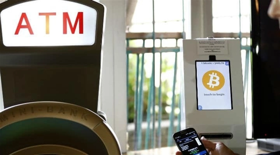 Bitcoin ATM with a warning sign indicating potential illegal activity.